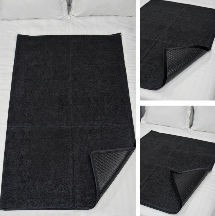 Black intimate Pleasure Pad with soft touch surface on a white bedding